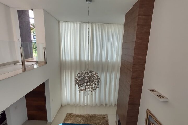 Cortina translúcida em sala com pé-direito duplo: a automação permite controlar a entrada de luz com um comando.